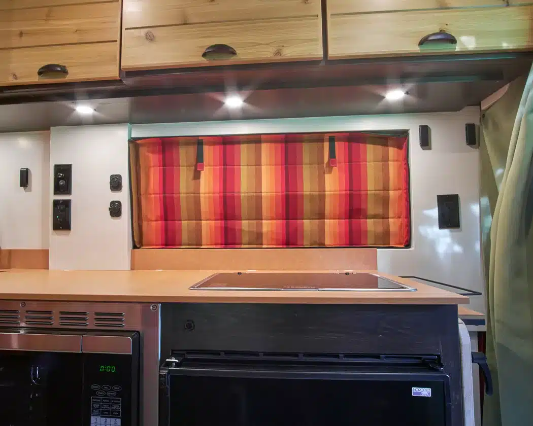 Beautiful interior of a professionally converted off-grid ready RAM ProMaster van from the team of Camp N Car located in Port Townsend on Washington's Olympic Peninsula custom window cover